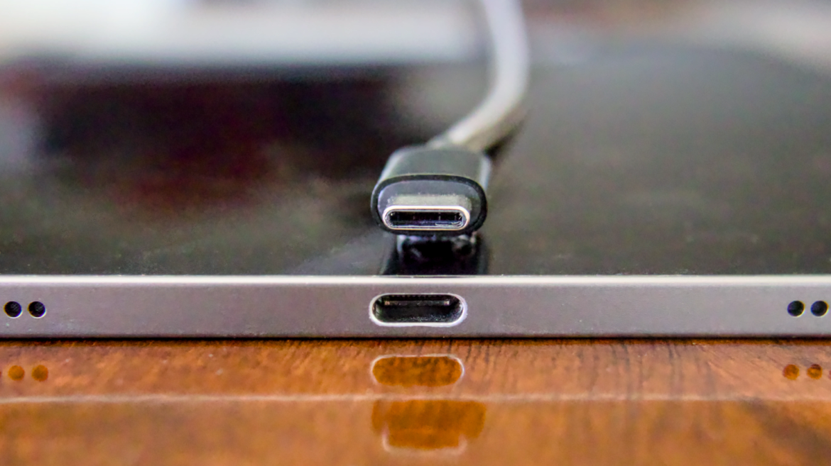 Conector de um cabo USB-C próximo à porta USB-C de um iPad Pro, visto de frente.
